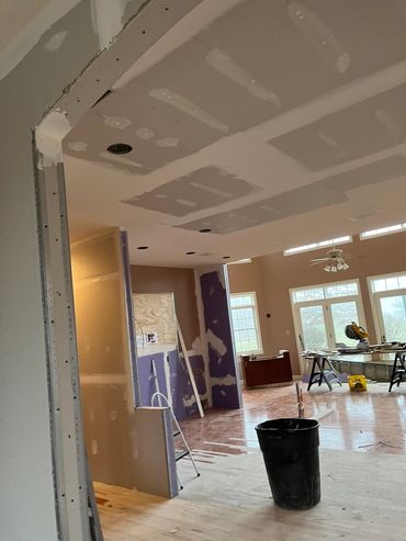 Room under renovation with exposed drywall and construction tools.