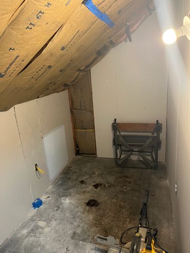 A renovation space with insulation, drywall, and light bulb.
