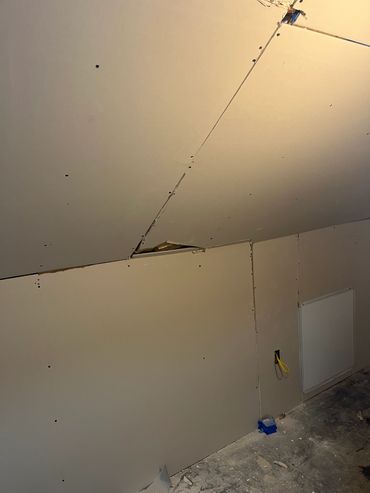 Unfinished drywall installation with visible seams and screw holes.