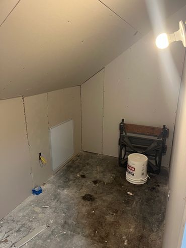Room with drywall installation in progress and a bucket on the floor.