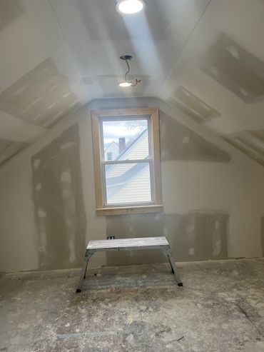 Room under construction with a window and a small bench.
