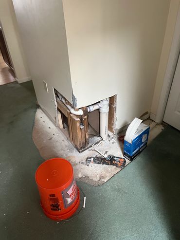 Plumbing repair site with exposed pipes and tools.