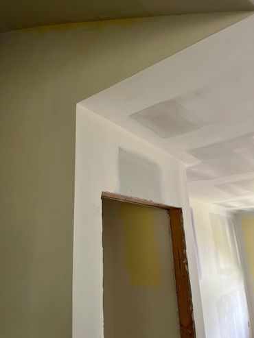 Partially painted yellow wall next to white unpainted drywall.