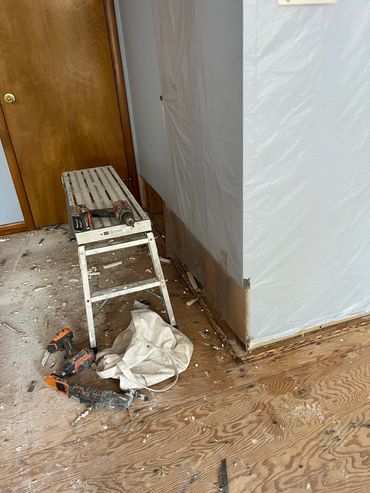 Room under renovation with tools and plastic-covered walls.