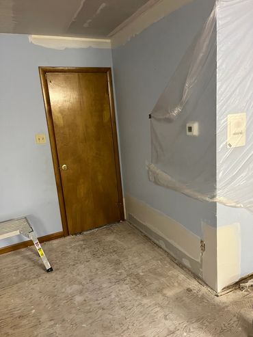 Room mid-renovation with bare floors and covered walls.