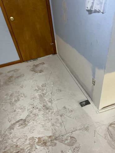 Dirty footprints on a dusty floor near a wooden door.