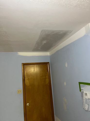 Ceiling with a patched area above a wooden door.