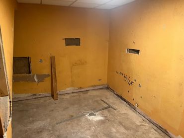 Empty construction room with yellow walls and dusty floor.
