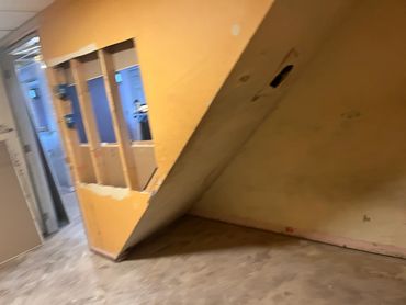 Room with exposed wooden framing and yellow walls under renovation.