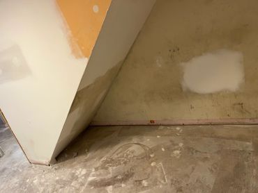 Wall and floor with worn and patched paint and plaster.