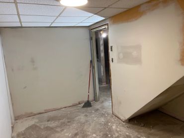 Room under renovation with a broom and unfinished walls.