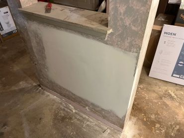 Half-painted wall with a countertop and construction materials around.