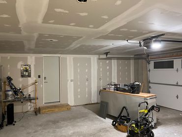 Unfinished garage with drywall and tools.
