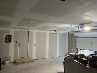Interior of an unfinished garage with drywall and a garage door opener.