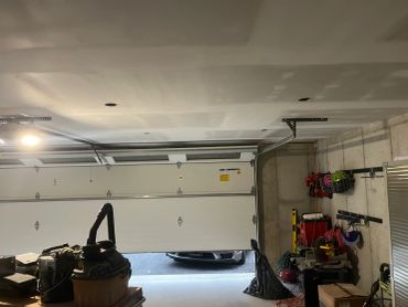 Partial view of an open garage door with tools and equipment.