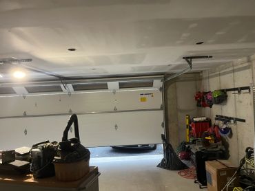 Open garage door with tools and helmets inside.