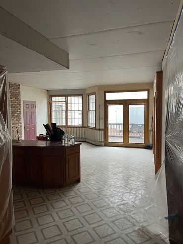 Room under renovation with plastic-covered furniture and exposed ceiling.