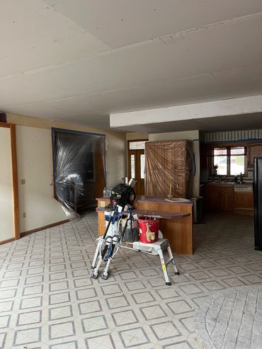 A room under renovation with plastic-covered cabinets and tools.