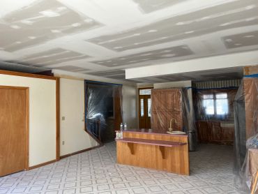 Interior renovation with drywall and furniture covered in plastic.