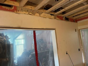 Room under renovation with exposed ceiling and partially removed wallpaper.