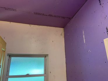 Room corner with purple drywall and window.