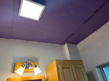 Purple ceiling with bright light and wooden cabinet.