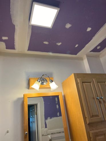 Bathroom with unfinished purple ceiling and lights.