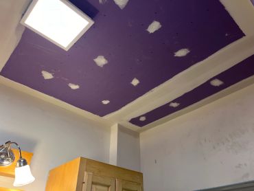 Purple ceiling with patchwork and light fixture.