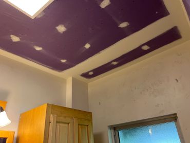 A purple and white ceiling with patchwork above a wooden cabinet.