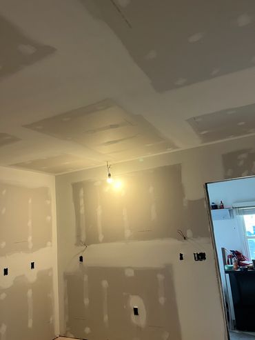 Room under construction with drywall and exposed bulb.