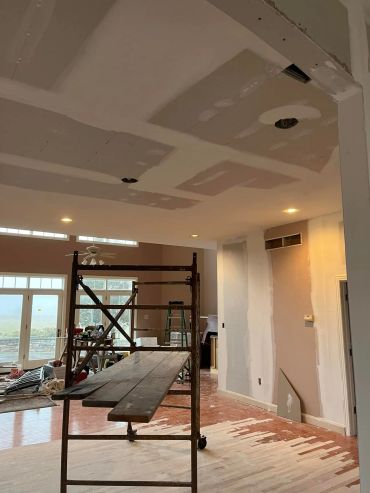 Room under renovation with drywall and scaffolding.