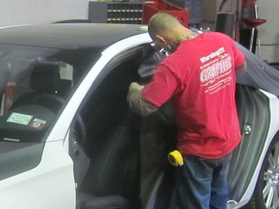 A man in a pink shirt wrapping a car