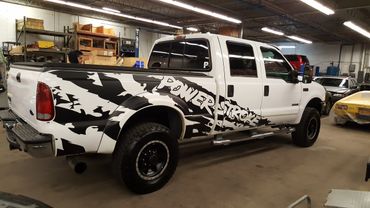 A white pick-up truck with black stripes and "Powerstroke" text in vinyl wrap