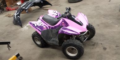 A children's toy motorbike with pink and purple skin