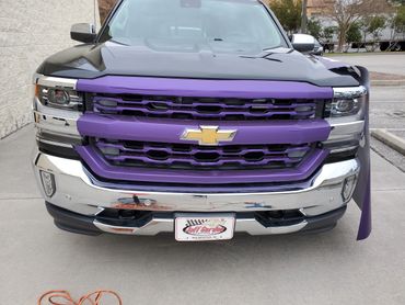 A black Chevrolet with purple custom grill skin