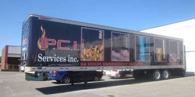 A tractor trailer for PCI Services with vinyl wrap showing fire, smoke, water, and more