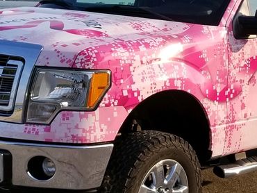 A pick-up truck covered in pink skin with ribbon design for breast cancer awareness