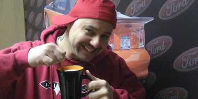 A man in a red hoodie holding a mug