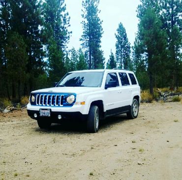 A white jeep/SUV with a striped custom grill skin