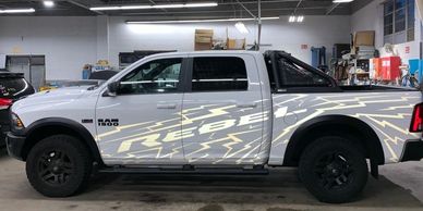A white pick-up with a white "Rebel" wrap