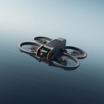 Compact black quadcopter drone flying over calm water surface.