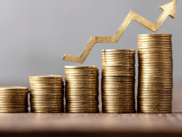 Stacks of coins with upward arrow showing financial growth.
