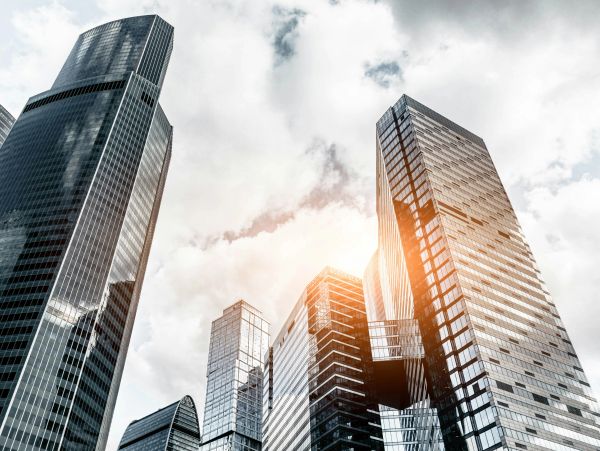 Modern skyscrapers under a cloudy sky with sunlight.