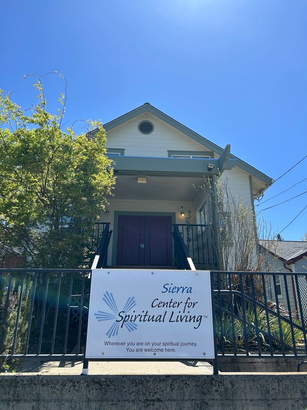 The Sierra Center for Spiritual Living, a yellow a-frame building with green trim, a tree, sunshine.