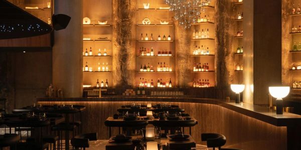 Dimly lit bar with bottles on illuminated shelves.