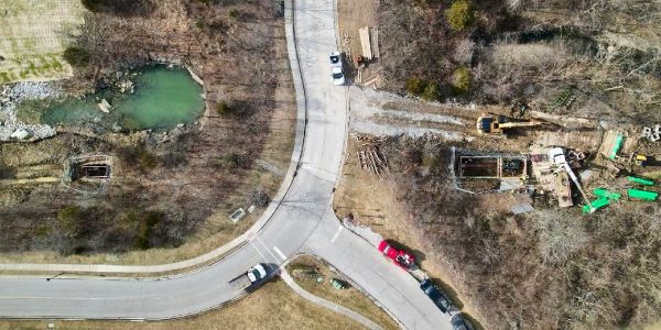 Aerial view of a road intersection with vehicles and a small pond.