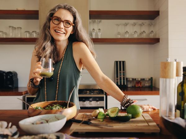 Middle aged women in kitchen drinking healthy smoothie