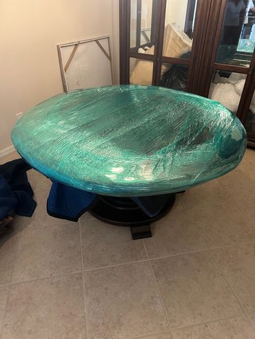A round table wrapped in protective plastic film.