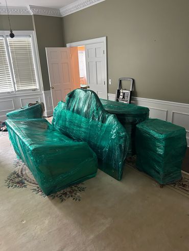 Furniture wrapped in green plastic in a room with beige walls.