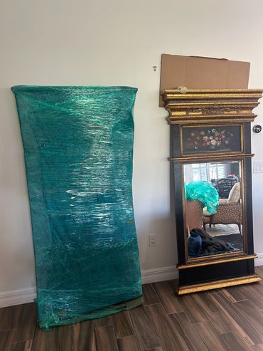 A wrapped mattress next to a decorative mirror.